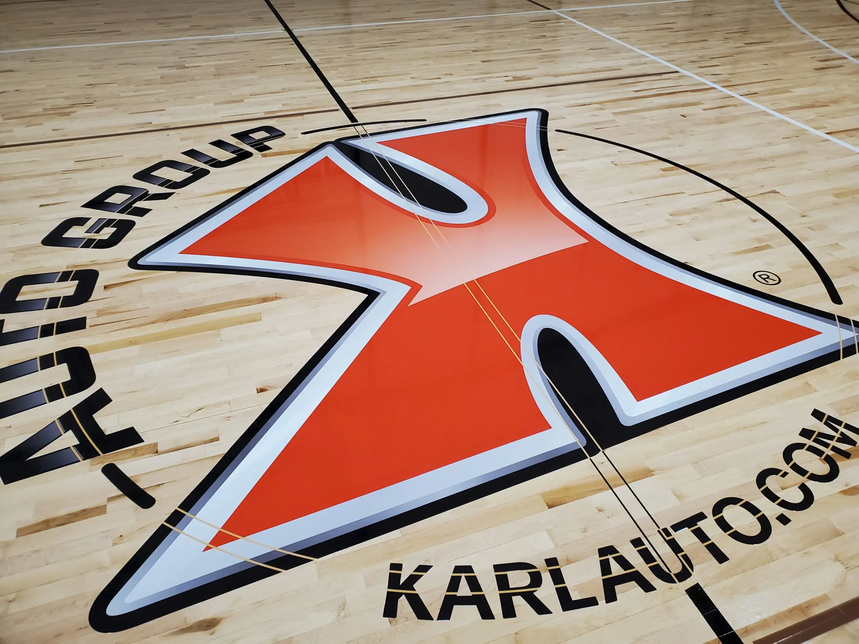 A large orange and white logo on the floor of a basketball court.