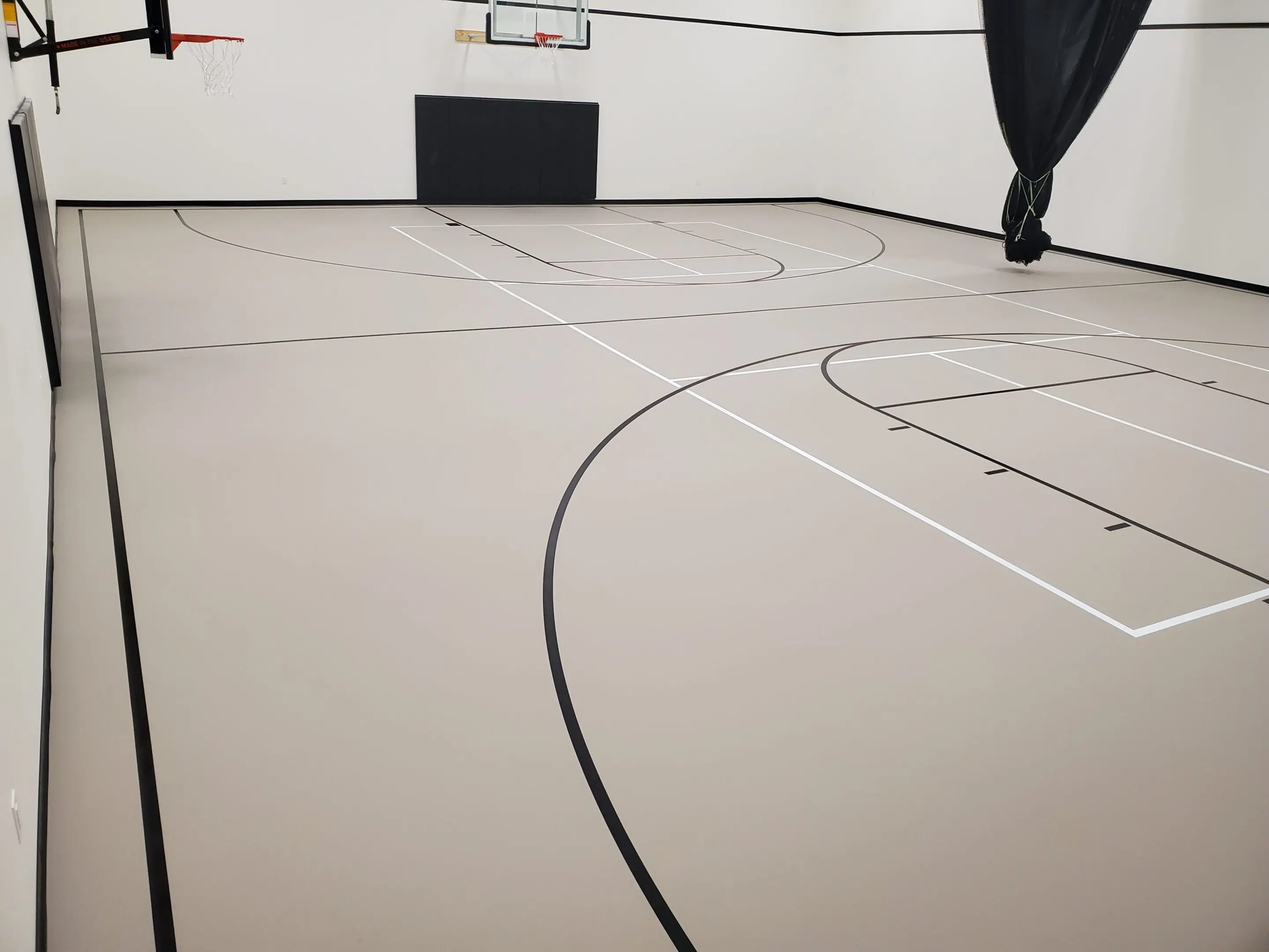 A basketball court with black lines and white walls.