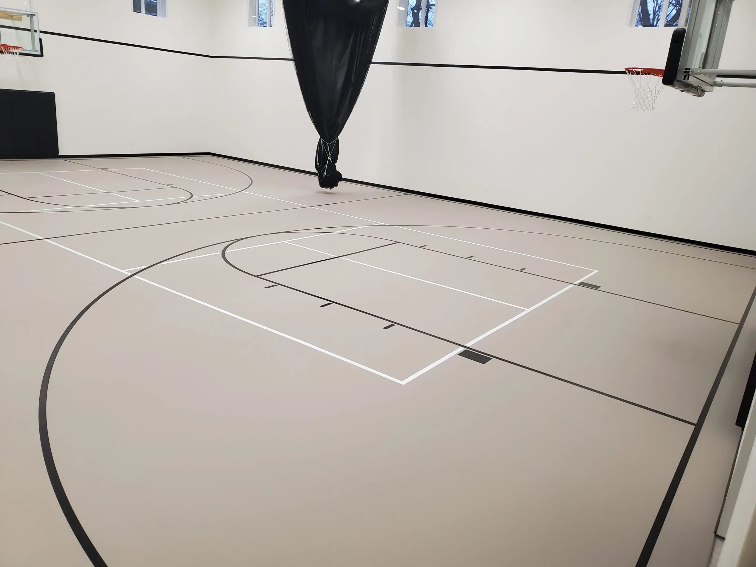 A person is walking on the floor of an indoor basketball court.
