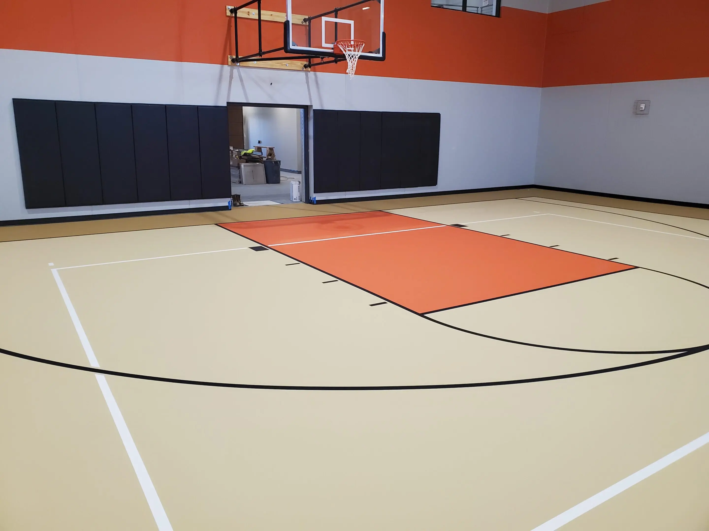 A basketball court with orange walls and black lines.