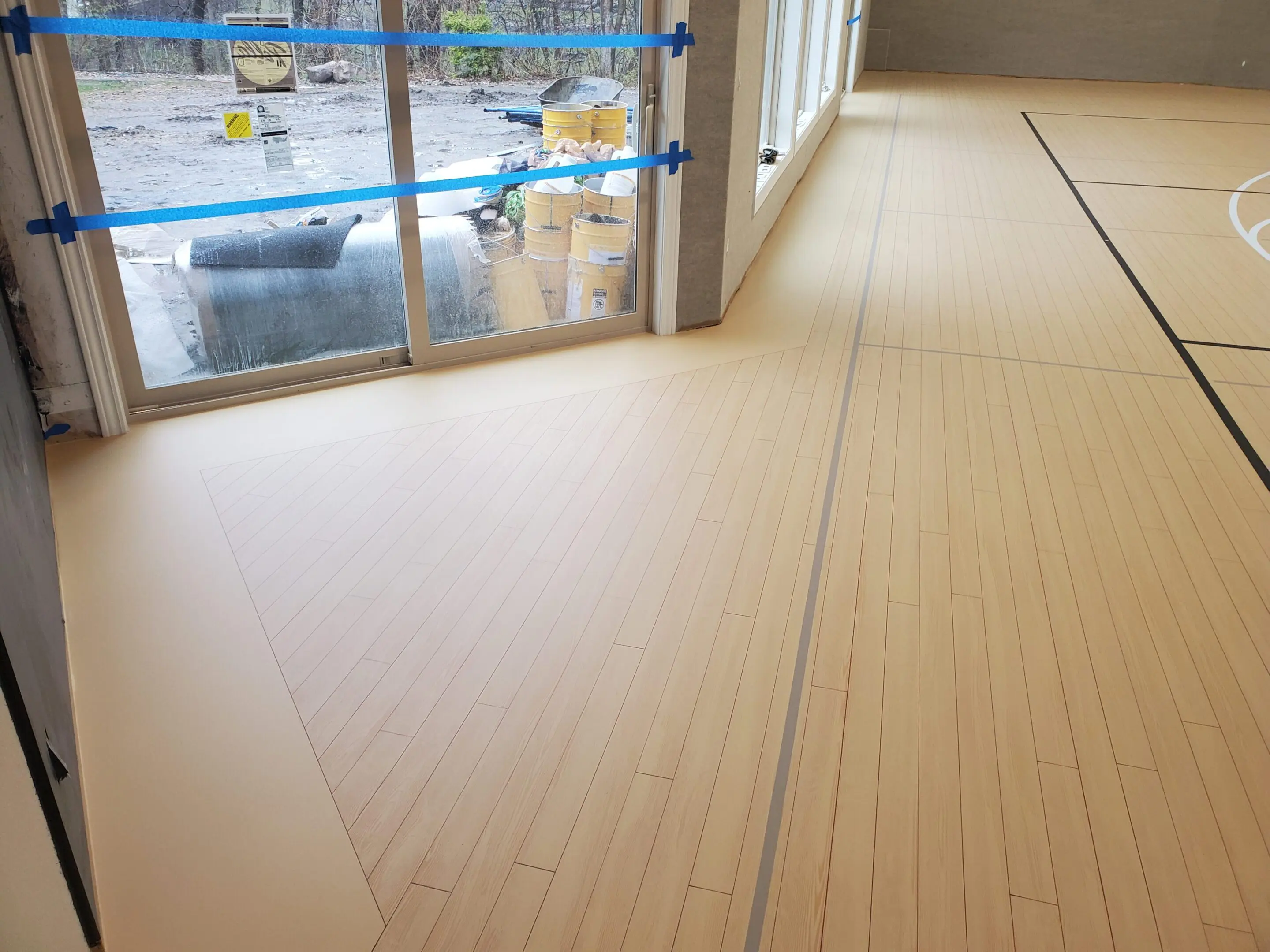 A room with a large window and wooden floors.