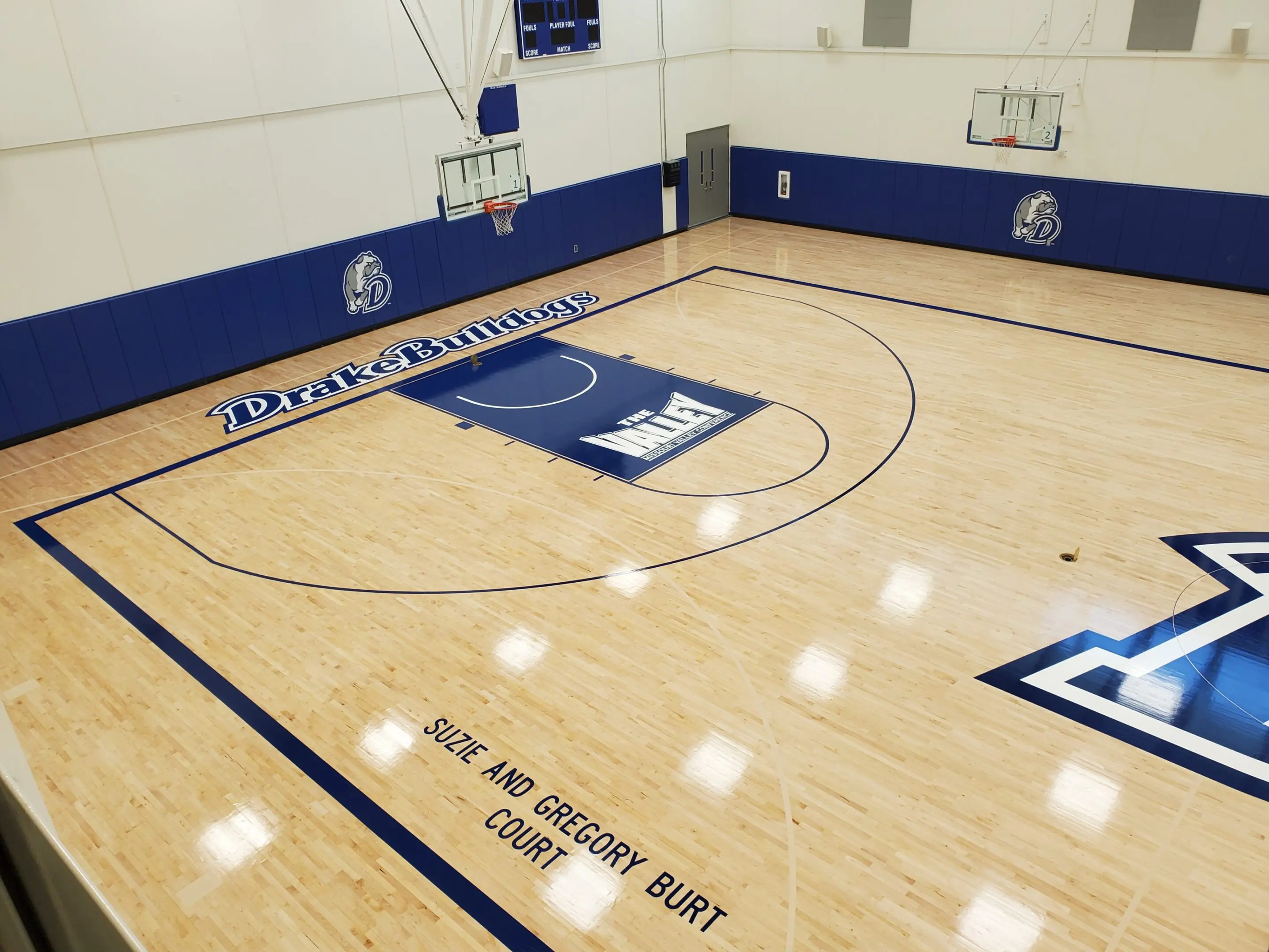 A basketball court with a blue wall and white floor.