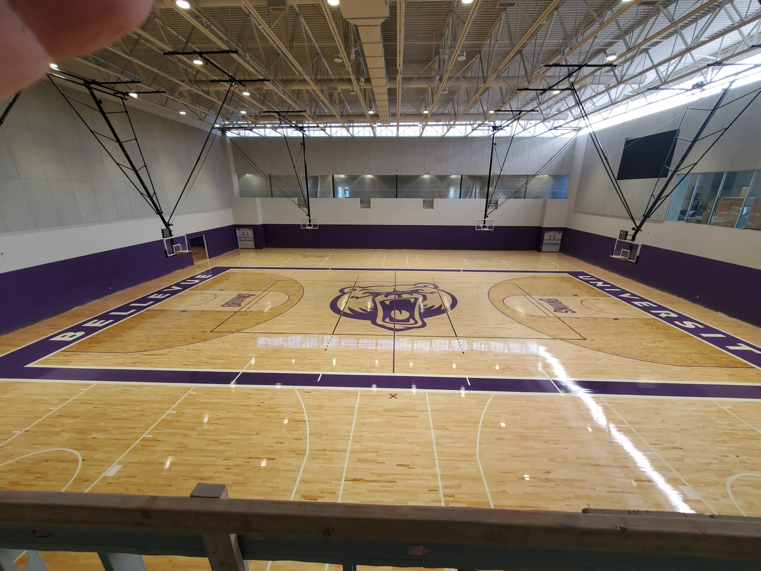 A basketball court with wooden floors and purple trim.