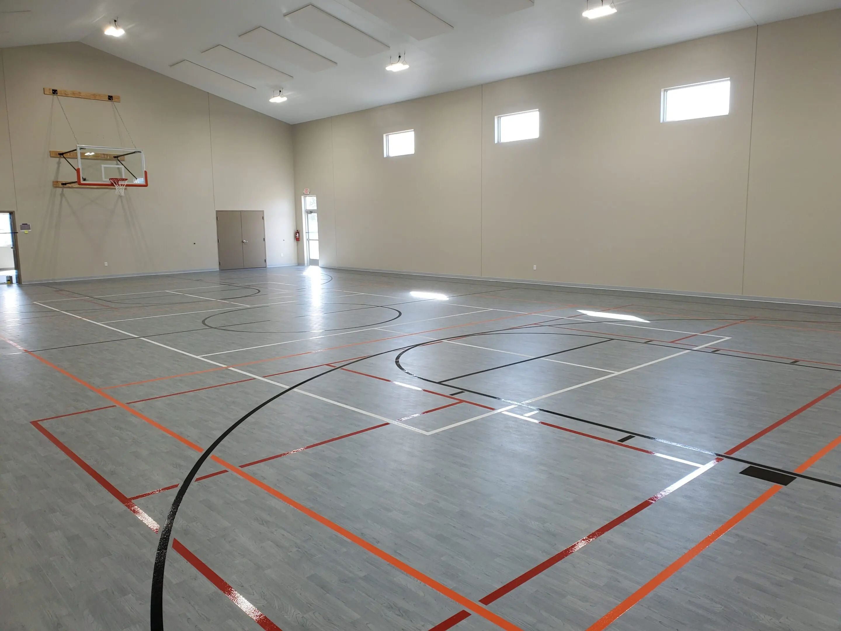 A basketball court with orange lines on the floor.