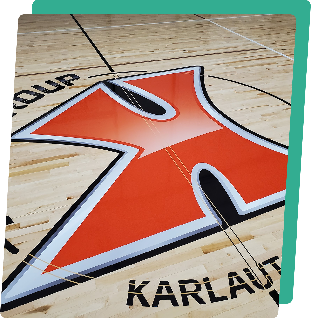 image2-1 A large orange and white logo on the floor of a gymnasium.